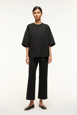 Woman wearing a black oversized knit t-shirt with matching cropped pants.