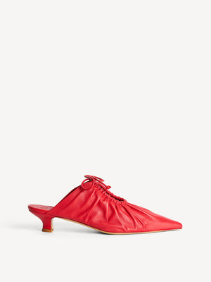 Side view of red leather mule with cinched detail on top.