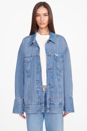 Up close of model wearing the biggest jean jacket in mid blue denim.