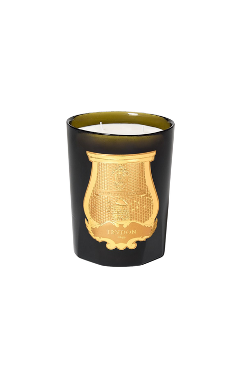 A green murano glass candle jar with a gold crest emblem on the front and a white wax surface visible at the top, isolated on a white background.