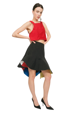 A woman wearing a red sleeveless crop top and a black skirt with colorful lining