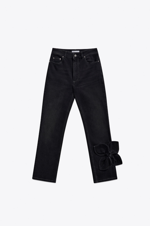 Black jeans with denim bow embellishment near the ankle on a white background