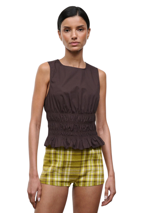 Woman wearing a brown sleeveless ruched top on a white background close up