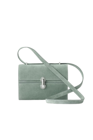 A mist green suede crossbody handbag that features a silver hardware twist lock and a crossbody strap.