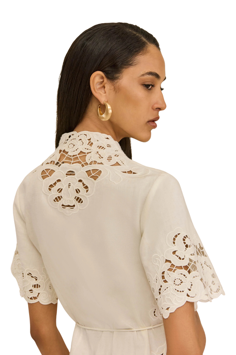 Woman wearing a white linen embroidered dress back angle close up