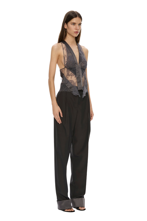 A model wearing a sleeveless black and gray sheer lace halter top paired with wide-leg black trousers and gray heeled sandals, photographed against a solid white background.