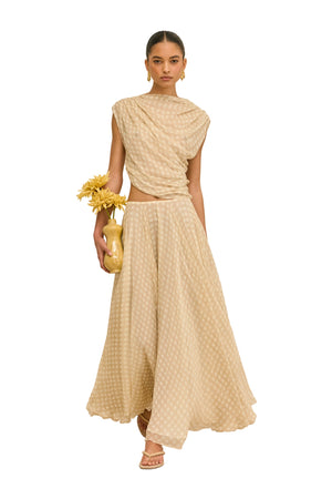 Woman wearing a beige checkered outfit holding a yellow clutch against a white background