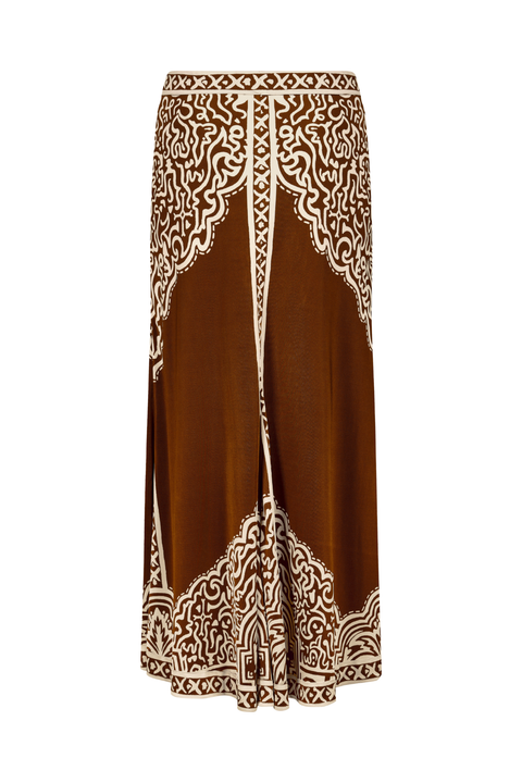A brown maxi skirt with intricate cream-colored bohemian-style embroidery and lace-like patterns along the front panels, waistband, and hem.