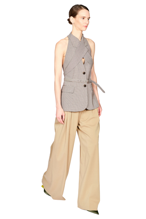 A model wearing a sleeveless gray and white checkered wrap vest with a tie belt, paired with beige wide-leg trousers, shown against a plain white background.