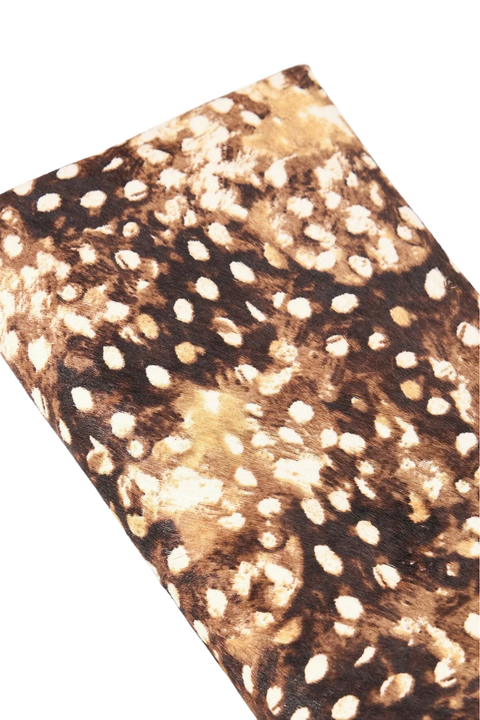 A close-up of a textured material featuring a brown and black spotted pattern with irregular cream patches, shown against a plain white background.