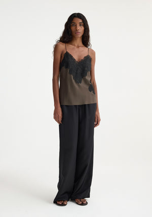 Model wears dark green tank with black lace detail and black pants.