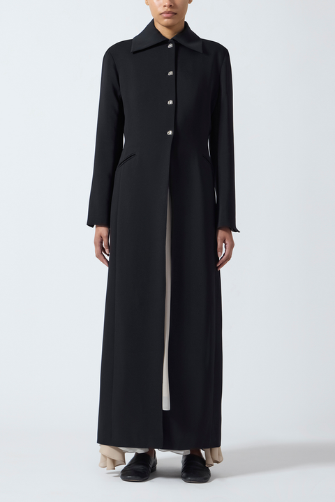 Black long coat worn by a person on a white background.