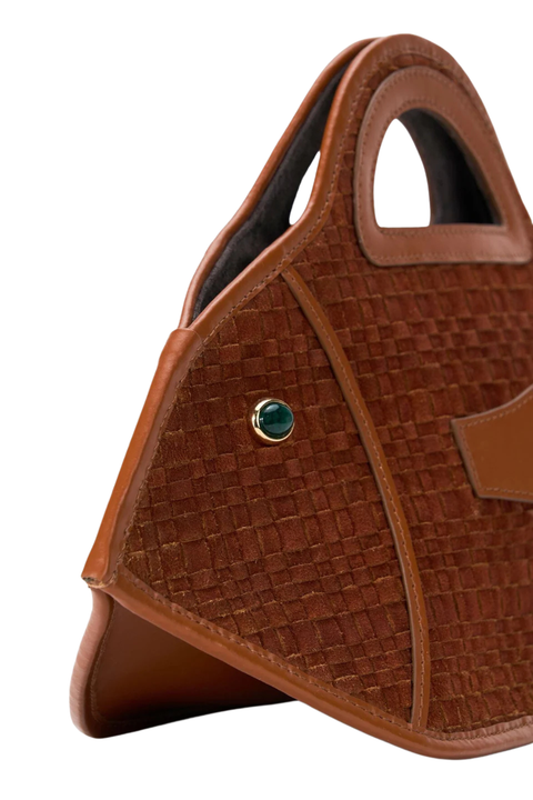 A close-up of a brown textured leather handbag with a small round green stone accent and gold-tone trim, shown against a plain white background.