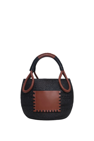 A small woven black straw handbag with brown leather trim, featuring a rectangular brown leather front patch and a curved brown leather top handle, shown against a plain white background.