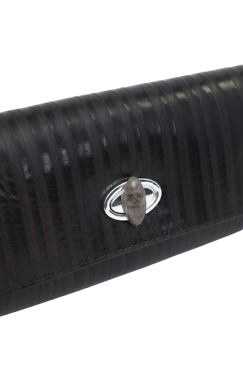 Close-up of a black textured leather clutch featuring a silver-tone oval ring clasp with a central gray stone.