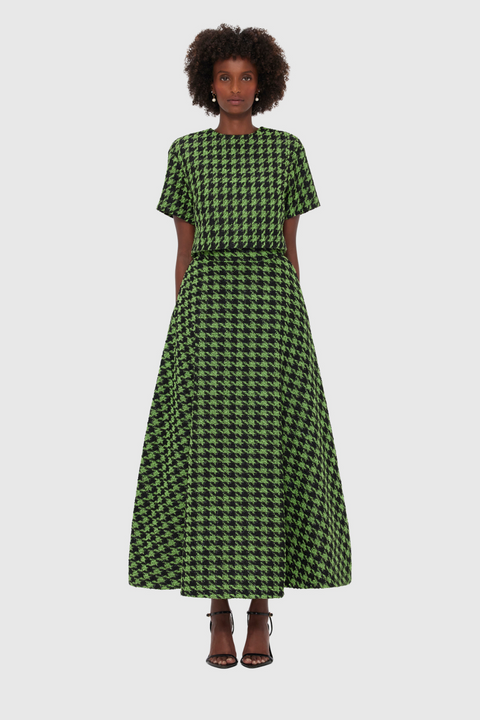 Woman wearing a green and black checkered top and maxi skirt on a white background