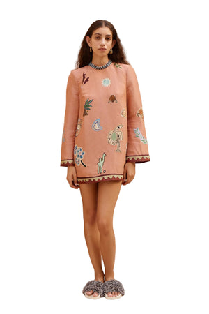 Woman wearing a coral dress with animal prints on a white background