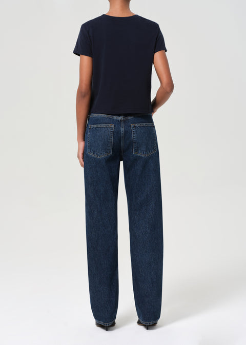 Person facing away showing back of a navy t-shirt and dark blue jeans on a white background