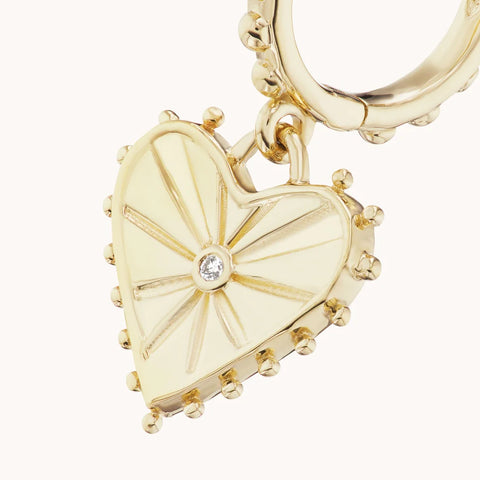 Up close look at heart dangle in yellow gold with small spikes and diamond in the center.