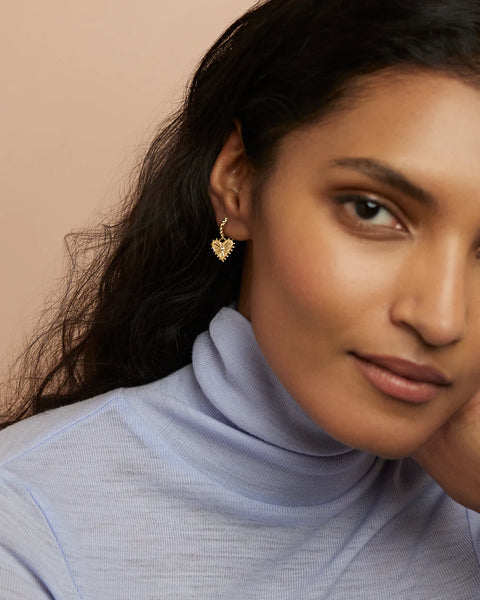 Model wearing small heart hoops.