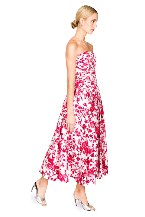 Woman walking to the right wearing a strapless floral dress on a white background