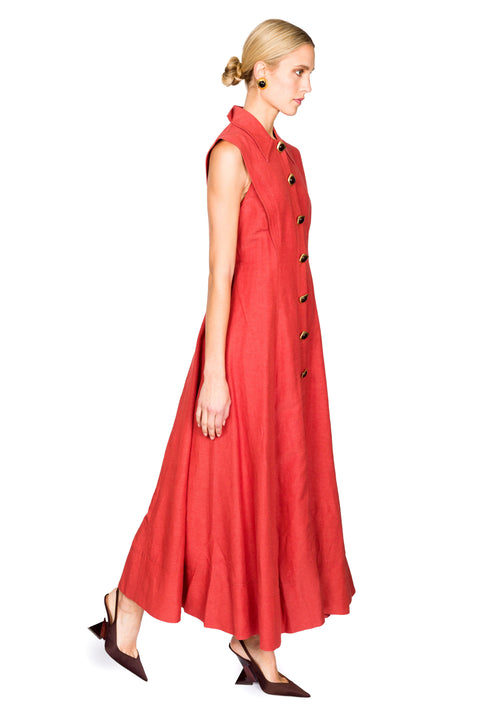 Woman walking to the right wearing a red sleeveless collared maxi dress with buttons on a white background