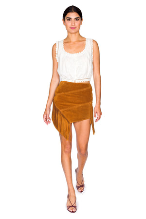 Model poses in white crochet trimmed cropped tank top and suede fringe skirt.