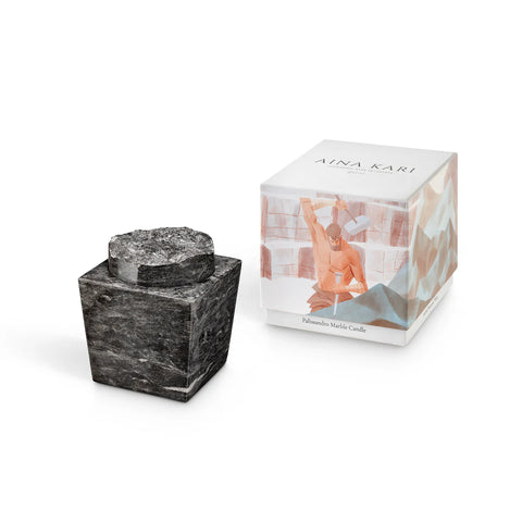 Black marble candle to the side of the Aina Kari box it comes in.