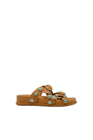 Tan sandal with decorative elements on a white background