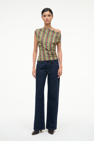 Woman wearing a colorful striped top and dark blue jeans on a white background