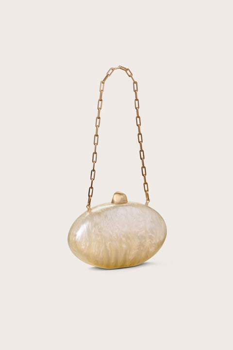 Side view of an oval-shaped clutch made out of pearlized acrylic, featuring gold hard wear and a detachable gold chain.