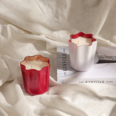 White and red murano glass candles styled on a book and linen cloth.