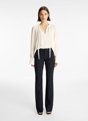 Model facing the camera in the off white silk blouse