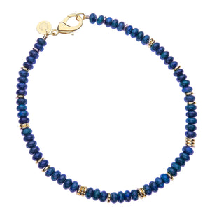 A blue lapis beaded necklace with a large gold lobster claw clasp.
