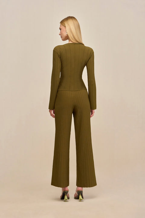 Back-facing woman wearing green ribbed wide leg pants with a matching long sleeve shirt.