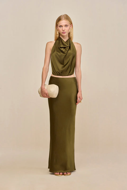 Woman wearing an olive green silk maxi skirt with a matching halter top.