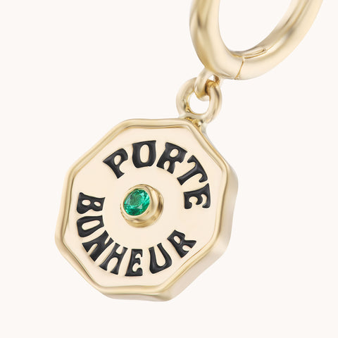 Up close of 'Porte Bonheur' coin earrings with small emerald.