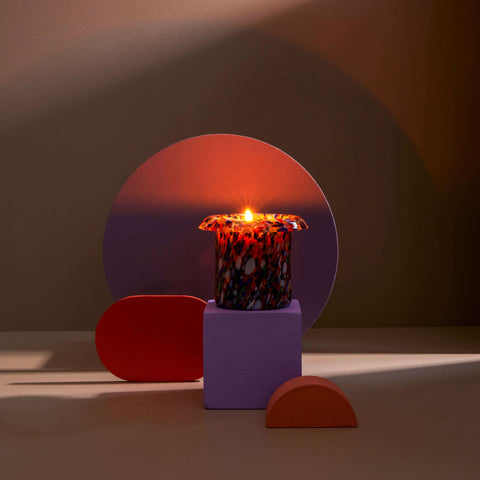 Lit candle surrounded by geometric shapes.