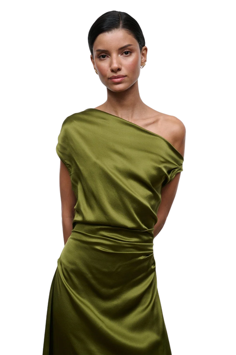 A woman modeling a one-shoulder olive green satin dress against a plain white background.