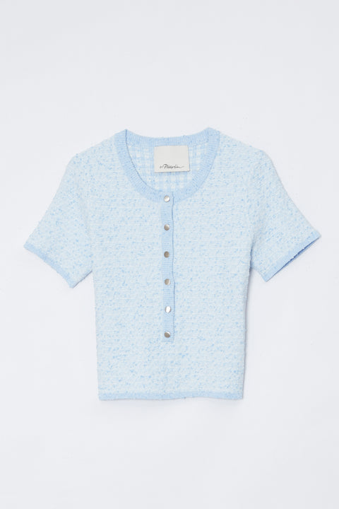 Flat lay of light blue top with buttons and dark blue jeans on a white background