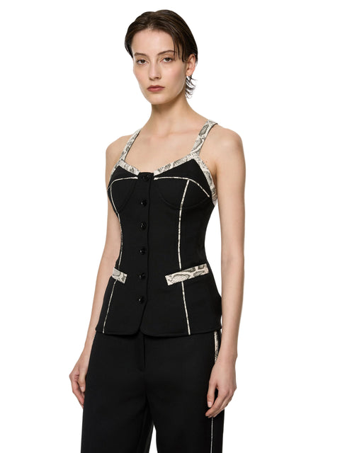 Woman wearing a black sleeveless top with snakeskin decorative trim on a white background