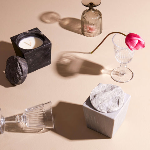 White and black marble candles surrounded by glassware.