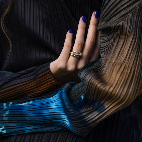 A woman wearing a Spinelli Kilcollin Petunia ring that features a 1.7mm sterling silver band, a 2.88mm sterling silver band pave with grey diamonds, and a 2.3mm sterling silver band, all connected with two 18k yellow gold connectors.