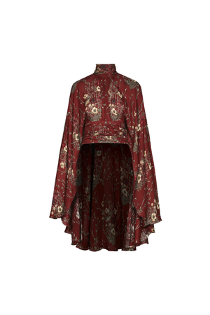 A high-neck, long-sleeve top with a high-low ruffled hem, featuring an intricate floral and paisley pattern in burgundy, gold, and beige, set against a plain off-white background.