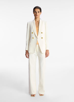 Full body view of a model facing the camera in the antique white double breasted blazer
