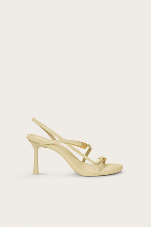 Side profile of a cream heel that features two gold buckle details and a slingback strap.