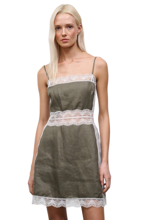 Close-up of a woman wearing a taupe-green mini dress with white lace detailing on the waistline and neckline