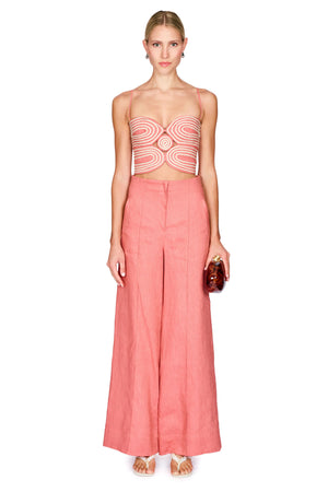 Woman wearing a pink strapless top and wide-leg pants on a white background
