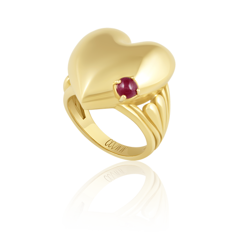 Gold heart-shaped ring with a red gemstone on a white background