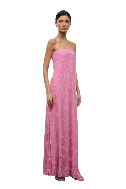 A woman wearing a strapless pink maxi dress with beaded embellishments side angle
